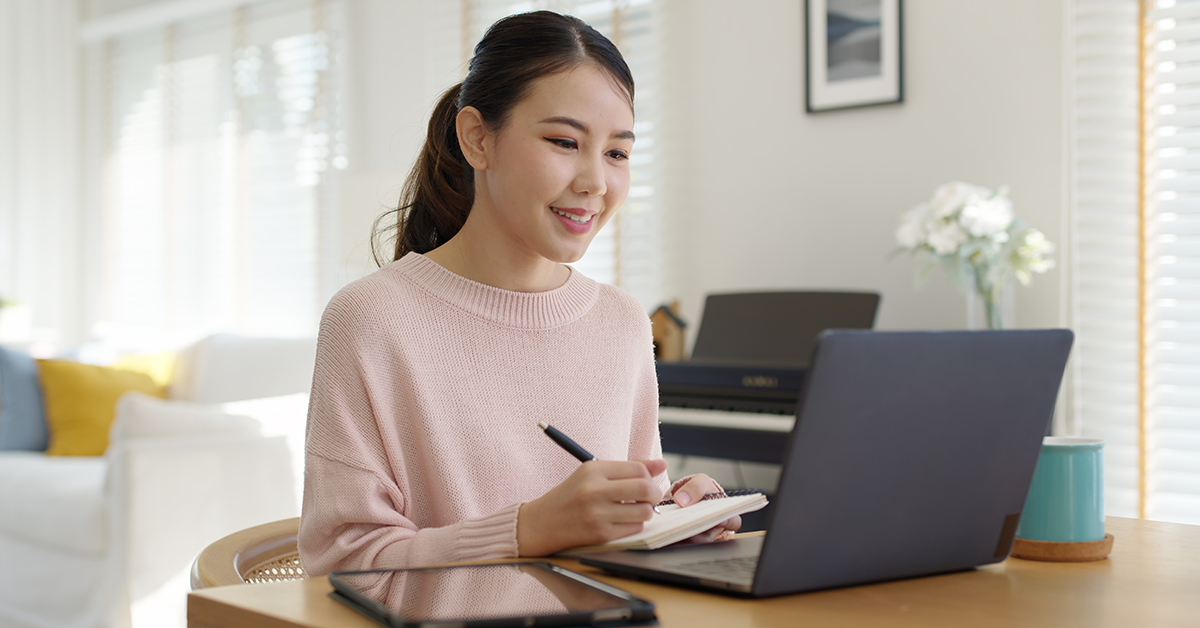 Woman working remotely from home sitting smiling in cozy workspace Woman working remotely from home sitting smiling in cozy workspace